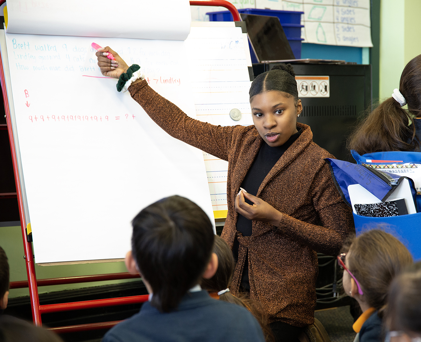Ms Bryant guides scholars through a math lesson on paper easel