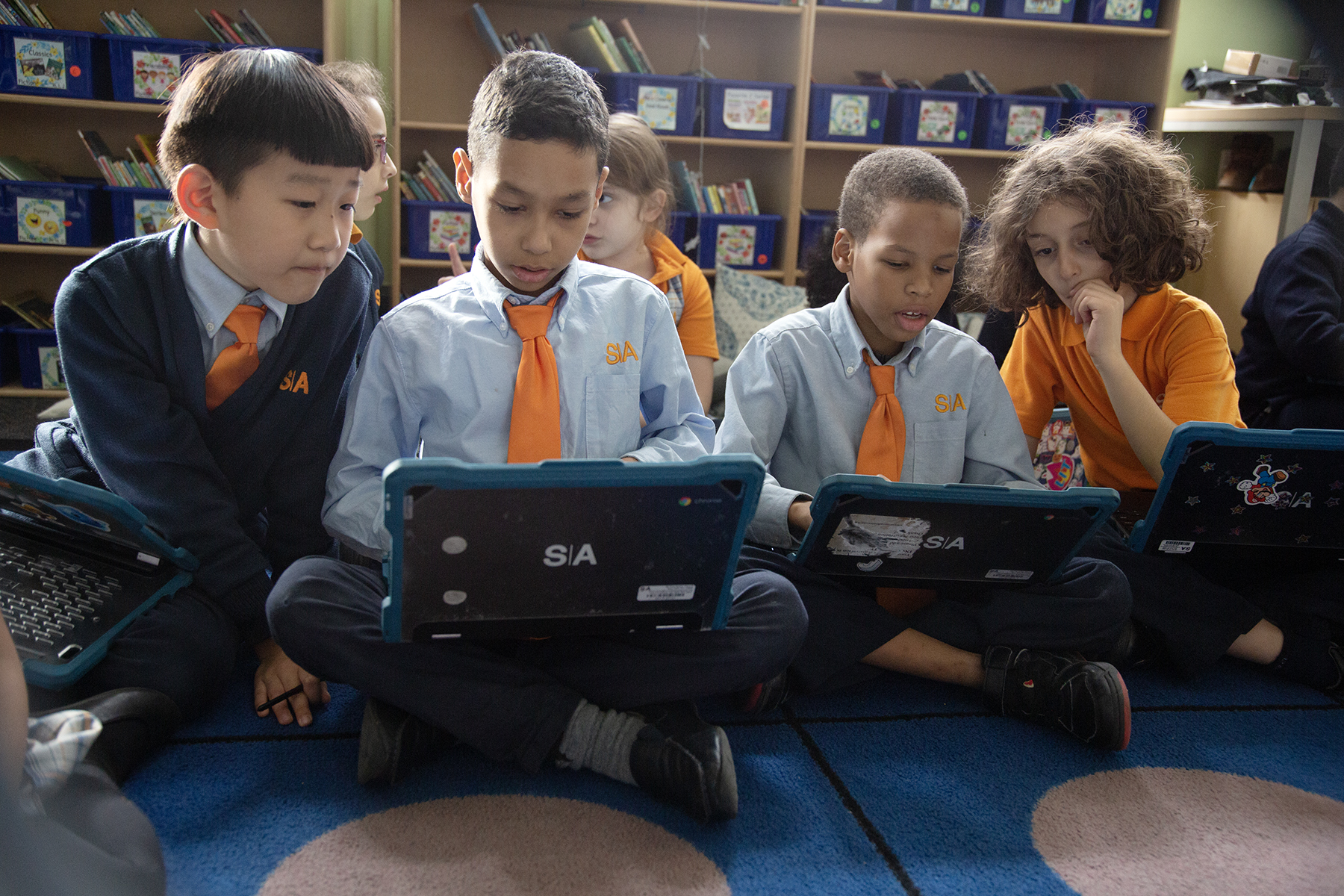 two scholars look to see what a third is doing on his Chromebook