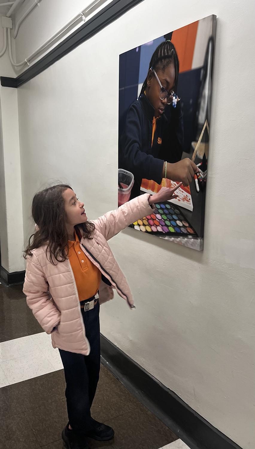 girl points to Pasca markers in giant canvas print of scholar in art class