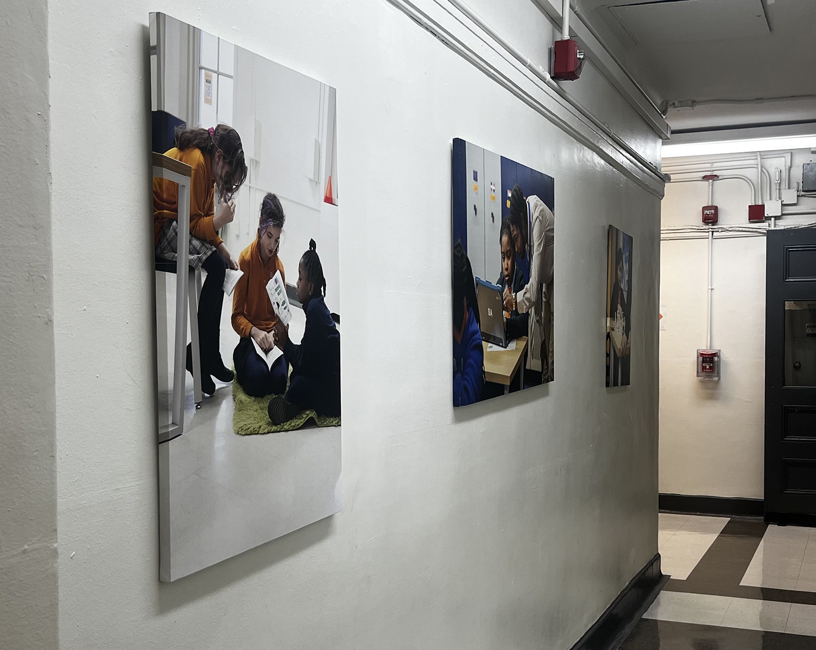 three canvases with art created by Madeline hangs on the wall in a middle school